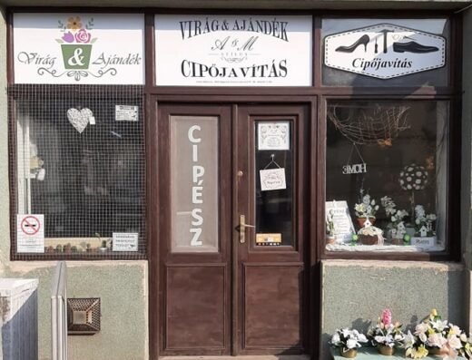 Virágüzlet és cipőjavító műhely közös bejárata virágokkal a kirakatban.
