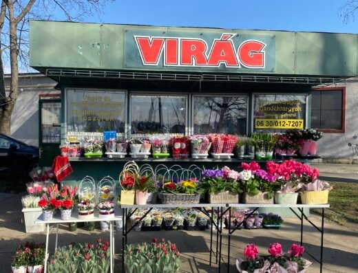 Virágbolt kirakata, színes virágokkal és koszorúkkal teli.